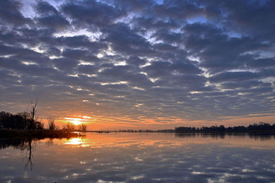View of calm lake against cloudy sky during sunset