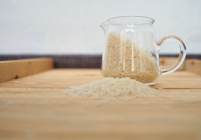 Close-up of rice in container on wooden table