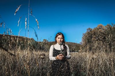 Portrait of young woman on field against sky