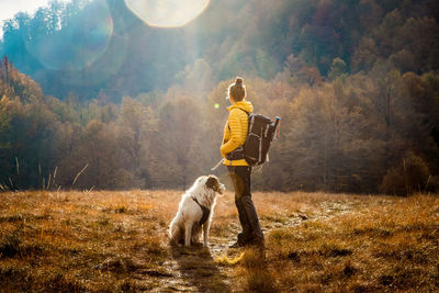 Full length of woman standing with dog on field