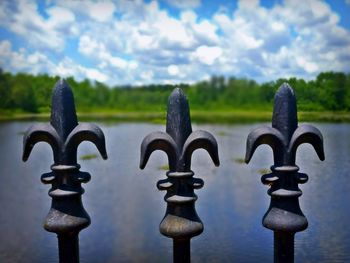 Close-up of metal gate against sky