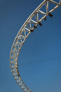 Low angle view of rollercoaster against clear blue sky