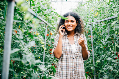 Young woman standing against plants