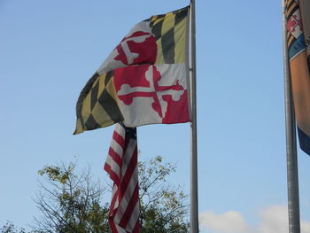 Low angle view of flags against clear blue sky