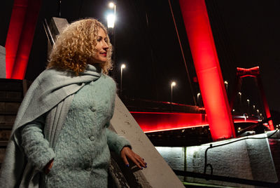 Woman looking at illuminated while standing at night during winter