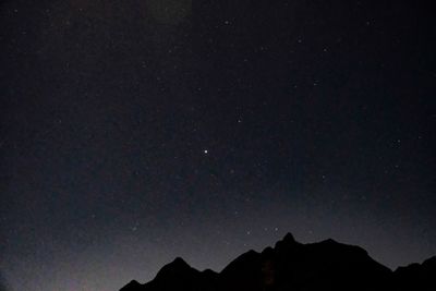 Low angle view of silhouette mountain against sky at night