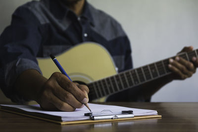 Midsection of man playing guitar on table