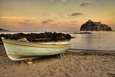 Boats moored on shore against sky during sunset