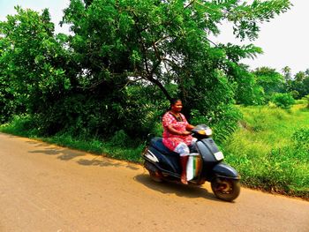 Rear view of woman riding motorcycle on road