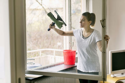 Woman looking through window at home