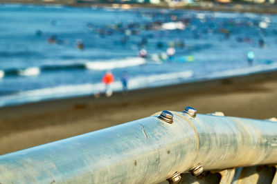 Close-up of pipe and people on beach