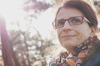 Close-up of smiling woman looking away sitting against trees