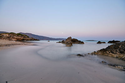 Scenic view of beach against clear sky during sunset