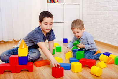 Cute boy playing with toy sitting on floor