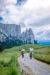 Rear view of man riding bicycle on mountain against sky