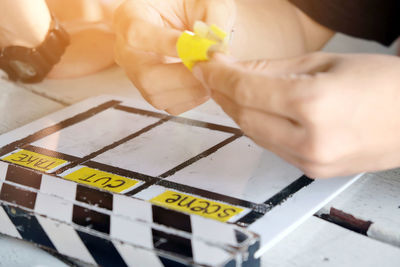 Close-up of cropped hands above film slate on table