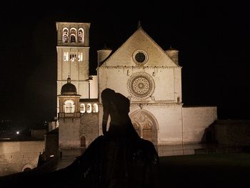 Silhouette people outside temple against sky at night