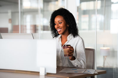 Portrait of smiling young woman using phone on table