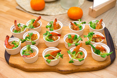 Fried prawns served in small ramekins on wooden board