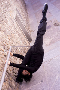 Low section of man hanging on railing against wall