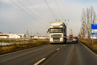 Vehicles on road against sky in city