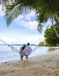 Asian women and caucasian men relaxing on a beach with palm trees on the island of koh mak thailand