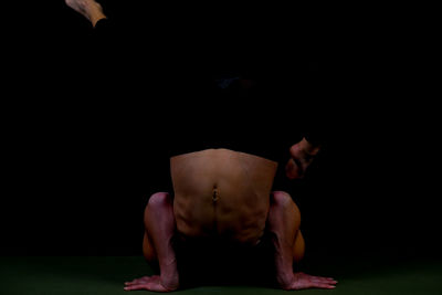 Athlete doing handstand on exercise mat against black background