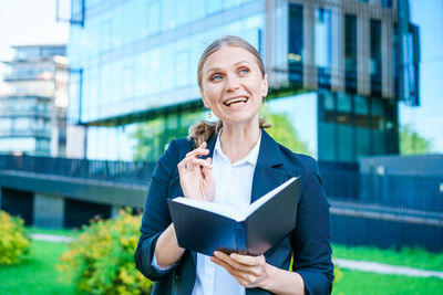 Successful business woman making notes in notebook outdoors in business