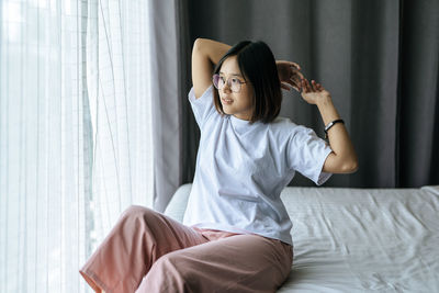 Young woman sitting on bed at home