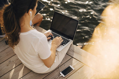 High angle view of woman using laptop while sitting with man at patio in holiday villa