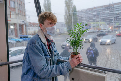 A young man in a mask on his face, does not like the current situation, moves in public transport