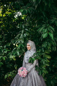 Portrait of woman standing by plants