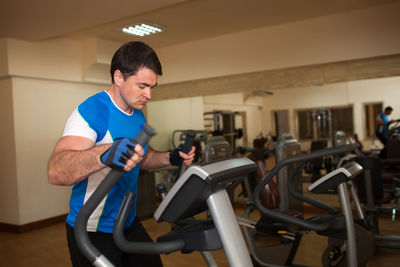 Young man exercising on machine in gym