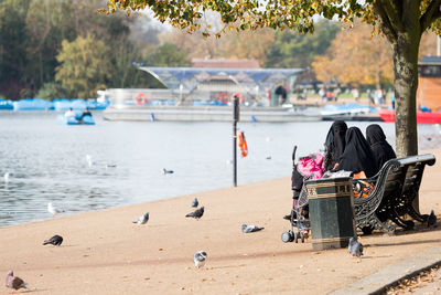 Woman in hijab sitting on bench by lake