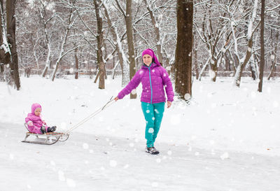 Full length of woman with umbrella on snow covered land