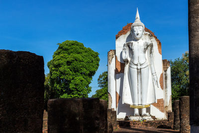Statue by building against clear blue sky