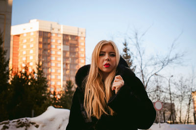 Portrait of woman in warm clothing against buildings