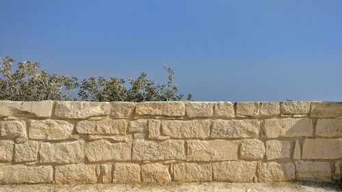 Low angle view of stone wall against blue sky