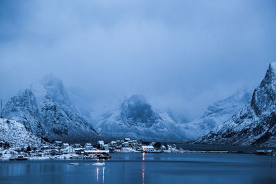 Scenic view of lake by snowcapped mountains against sky