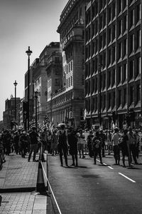 People walking on street amidst buildings in city