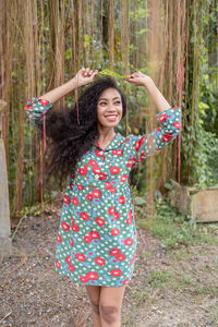 Young woman standing against trees