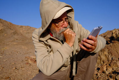 Senior man using mobile phone in the desert 
