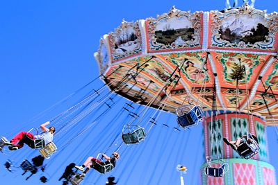 Low angle view of carousel against clear blue sky