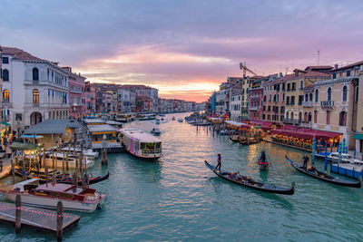 Boats moored in canal against buildings in city