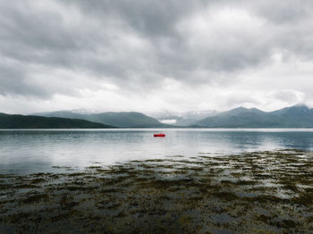 Scenic view of small boat in a fjord against sky