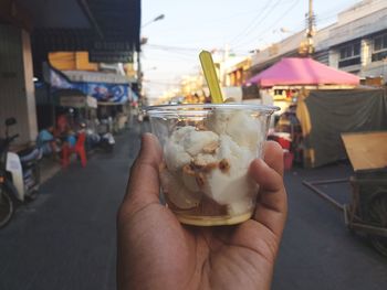 Close-up of hand holding ice cream on street in city