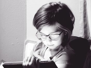 Girl using digital tablet while sitting against wall