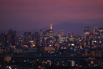 Illuminated tokyo tower in city against sky during sunset