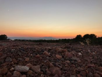 Surface level of pebble landscape against sky during sunset