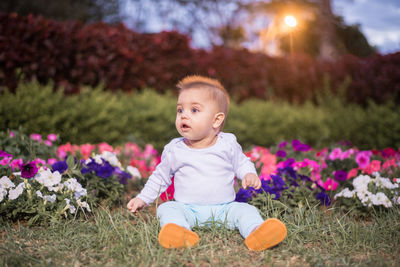 Portrait of cute baby girl sitting on plants